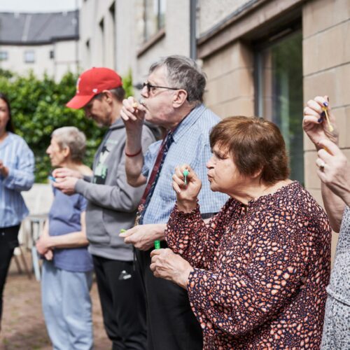 Older people blowing bubbles outside