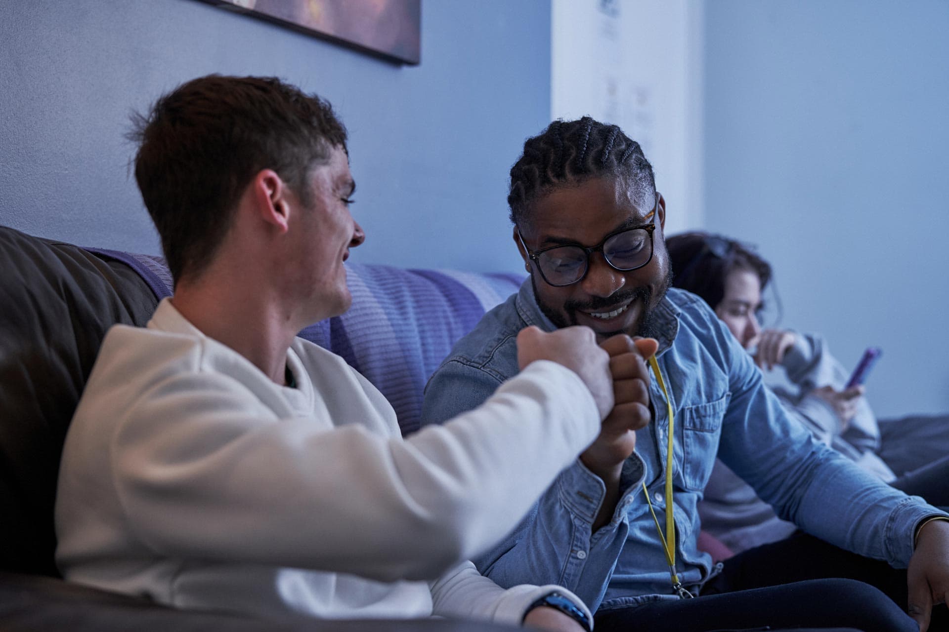 Two men sitting on couch fist bumping