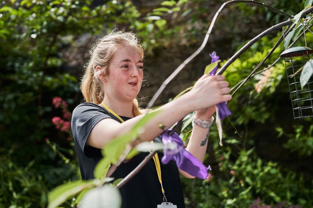 Woman tying ribbon onto a tree - thriving community with Care Support Scotland