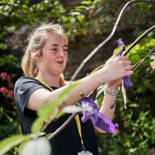 Woman tying ribbon onto a tree