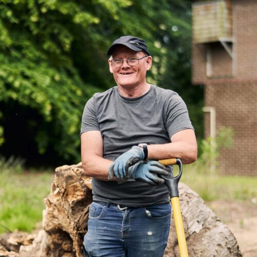 Man with shovel smiling outside