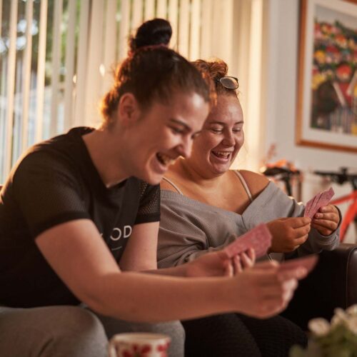 Two people smiling whilst playing cards