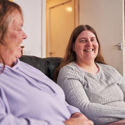 Two women smiling on a couch