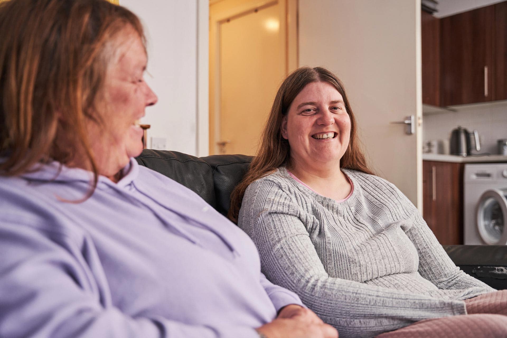 Two women smiling on a couch