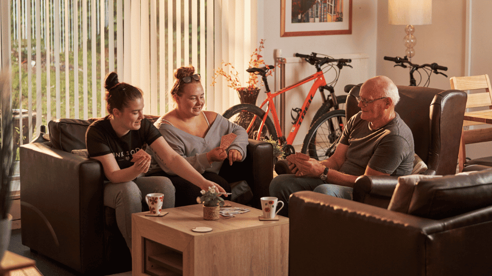 Care Support Scotland - three people enjoy a game of cards in a shared living space